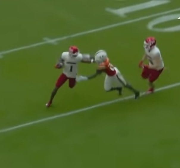 Broadcast frame, American football: a ball carrier stiff-arms a tackler