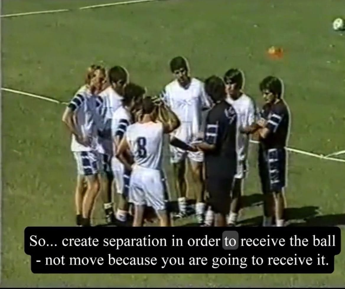 Video still of a coach talking to young players, subtitled: create separation in order to receive the ball, not move because you are going to receive it