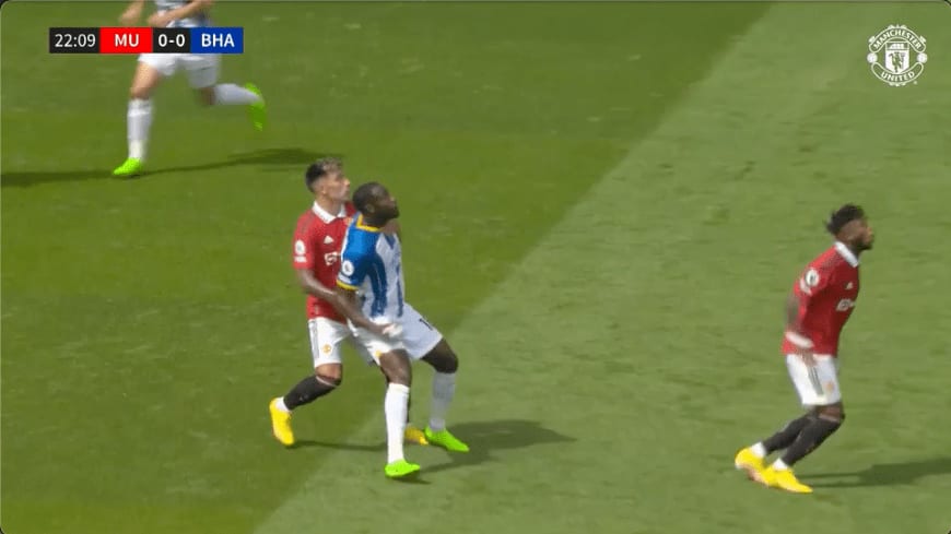 Broadcast frame, Manchester United v Brighton: just before the ball arrives, Lisandro Martínez and Welbeck both watch it in contesting position