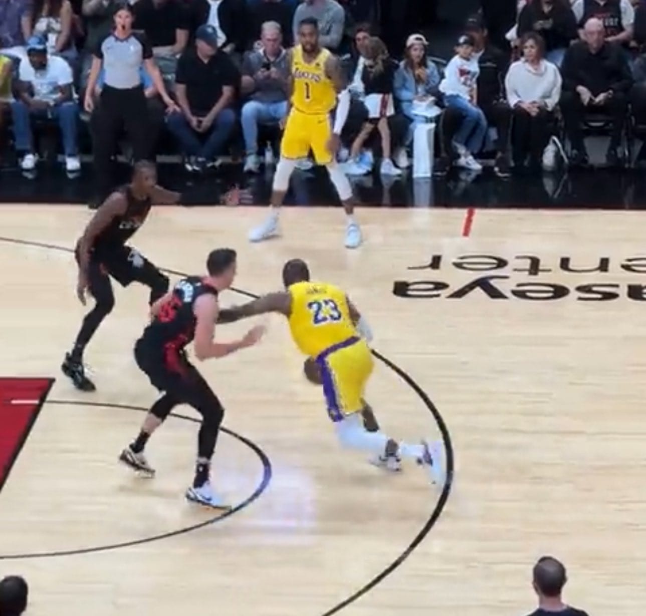 Broadcast frame, basketball: a Los Angeles Lakers player drives past a defender, holding him off with his arm